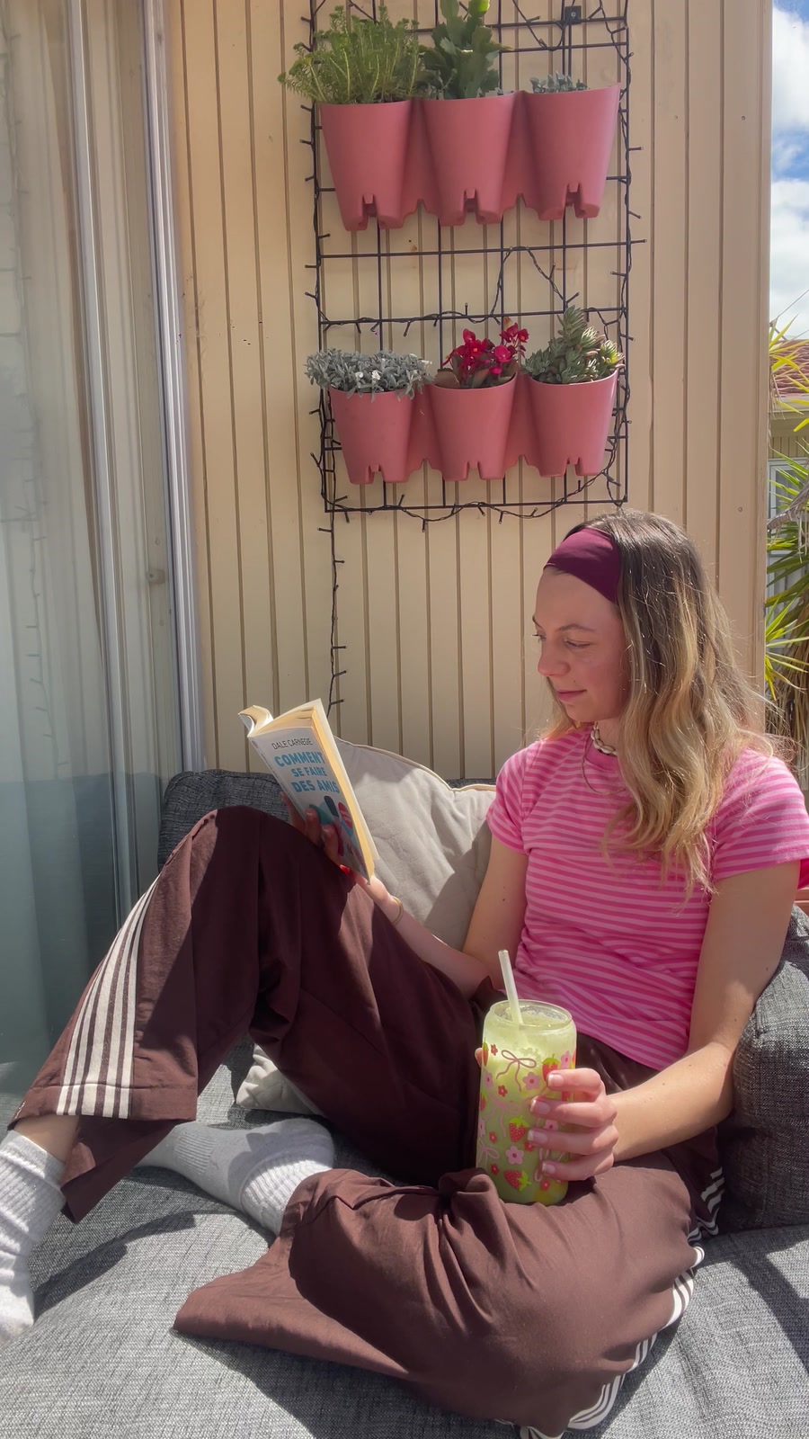 Emma reading with an iced matcha on her sunny balcony