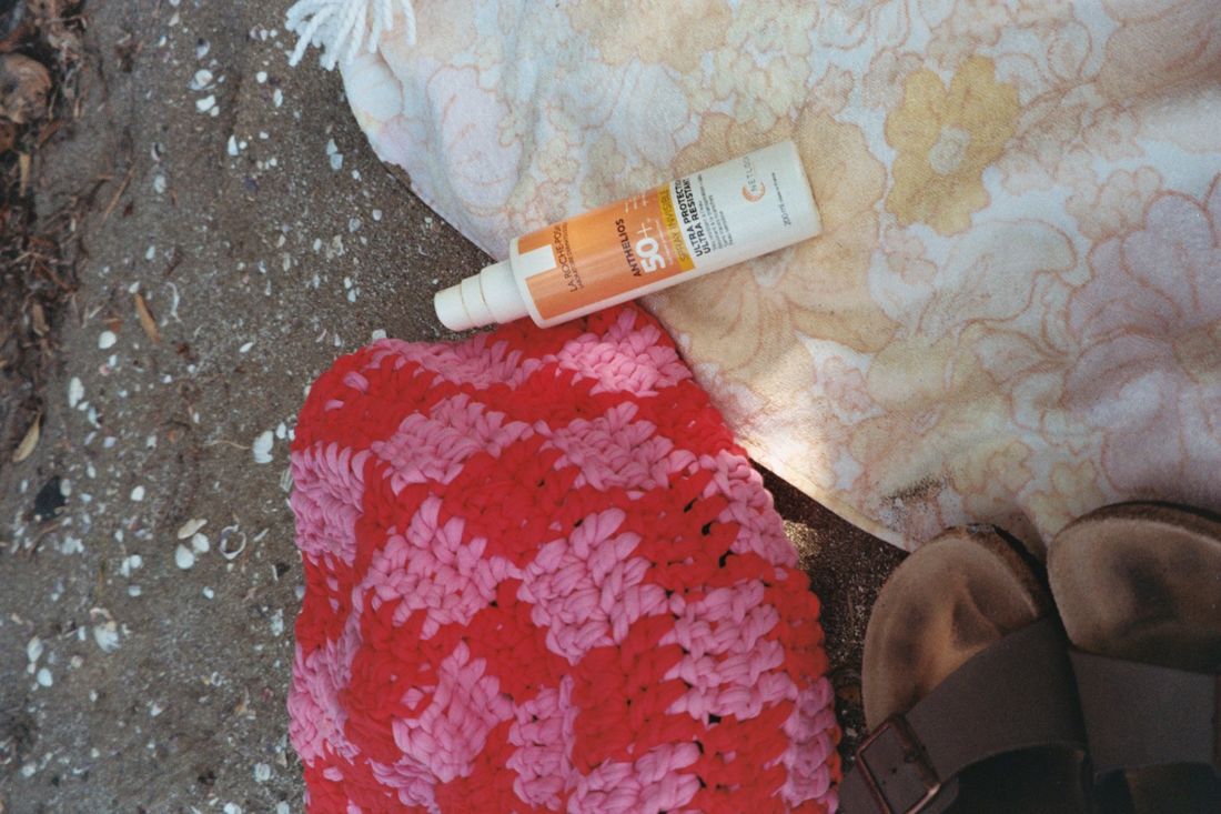 Sunscreen on a beach towel, styled flat lay